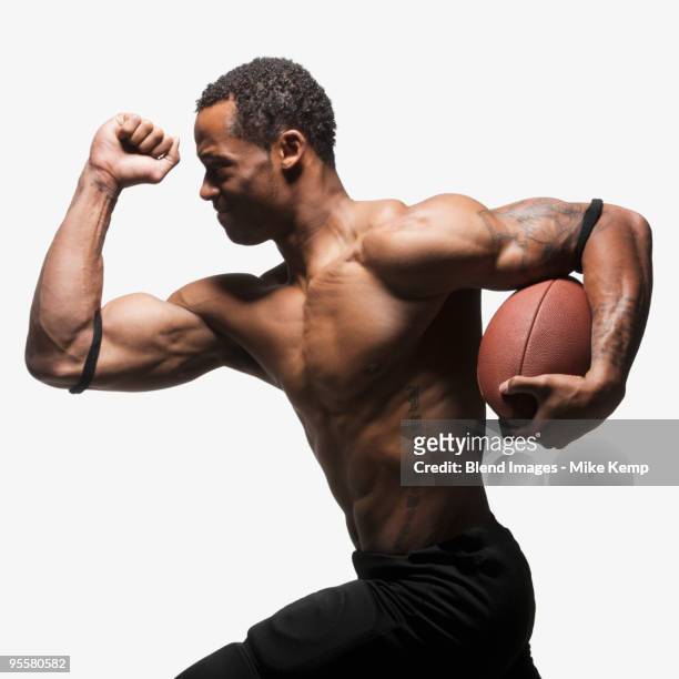 bare chested football player running with football - american football player studio stock pictures, royalty-free photos & images