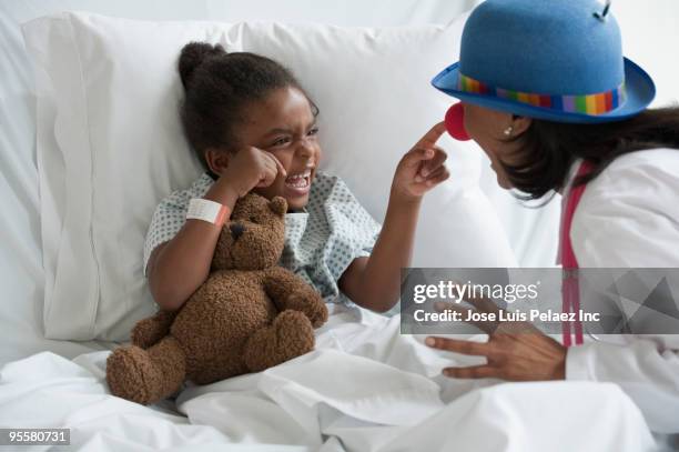 doctor entertaining girl in hospital bed - rapporto medico paziente foto e immagini stock