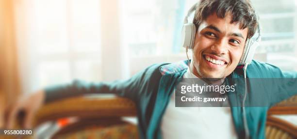 happy young man listening podcast - podcast headphones stock pictures, royalty-free photos & images