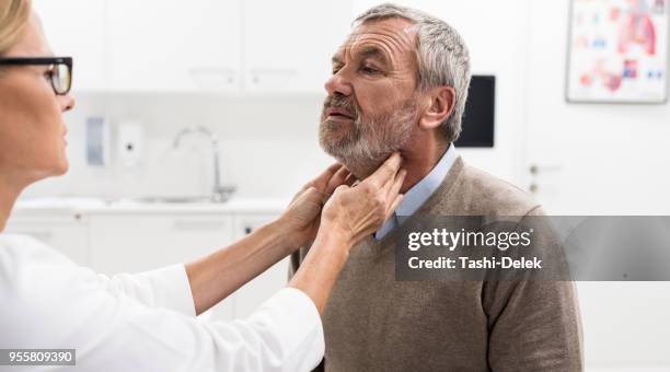 female doctor doing throat examination on older man - throat exam stock pictures, royalty-free photos & images