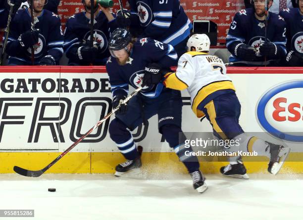 Patrik Laine of the Winnipeg Jets plays the puck along the boards as Yannick Weber of the Nashville Predators gives chase during second period action...