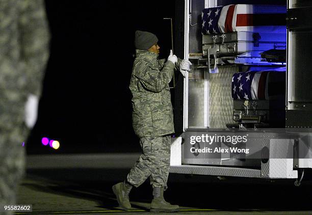 Air Force Senior Airman Zenna Tunnell closes the doors of a mortuary vehicle which carries flag-draped transfer cases of Army Sergeant Joshua...