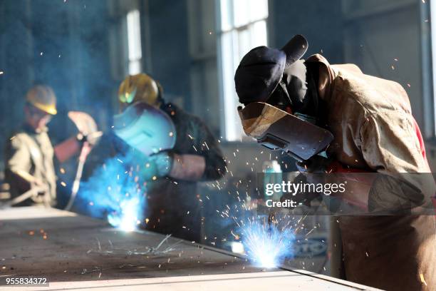 This photo taken on May 3, 2018 shows a worker cutting steel at a factory in Huaibei in China's eastern Anhui province. - China's surplus with the...