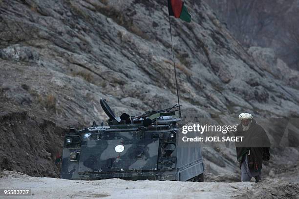 An Afghan man walks past an armoured personnel carrier of the Operational Mentoring and Liaison Teams of the Kandak 32 along the Alah Say road in...