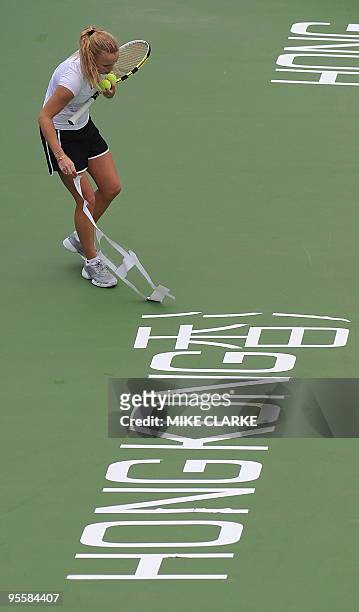 Caroline Wozniacki of Denmark removes plastic lettering from centre court after it caused her teammate Victoria Azarenka of Russia to slip during...
