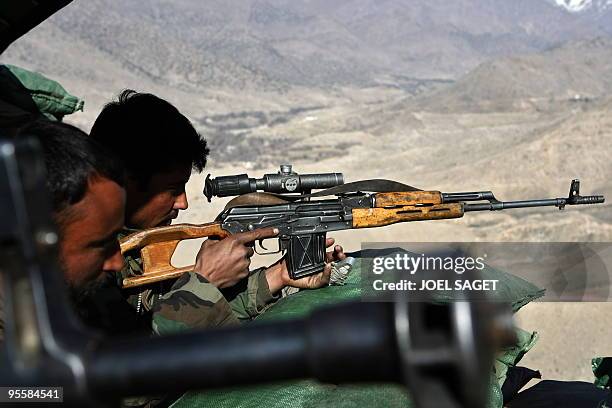 An Afghan National Army soldier from the OMLT of the Kandak 32 aims his Dragunov sniper rifle from an "Eagle's Nest" observation post in the Alah Say...