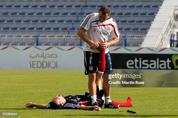 Physiotherapist Giovanni Bianci of Bayern Muenchen stretches Franck Ribery during the FC Bayern Muenchen training session at the Al Nasr training...