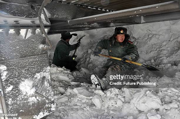 Army personnel and police officers work to dig out passenger carriages of a train that is trapped in snow on January 4, 2010 in Shangdu county in...