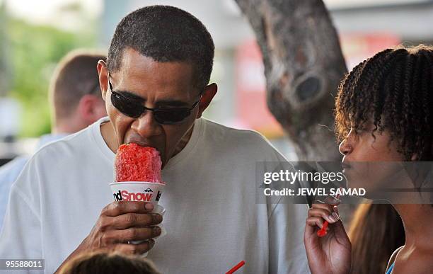 President Barack Obama has his shave ice as Malia looks on outside Island Snow store in Kailua, Hawaii, on January 1, 2010. The First Family are on...