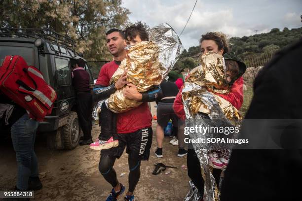 Salam Aldeen , a Danish founder of Team Humanity, and another volunteer carry children after helping to rescue migrants arriving on the Greek island...