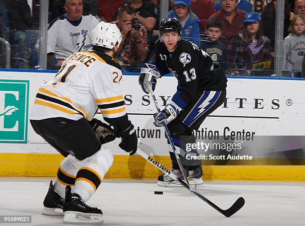 Alex Tanguay of the Tampa Bay Lightning skates with the puck against Andrew Ference of the Boston Bruins at the St. Pete Times Forum on December 28,...