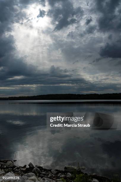sun breaking through the  clouds reflecting in the lake - mammatus cloud stock pictures, royalty-free photos & images
