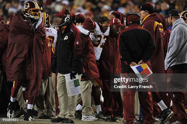 Reed Doughty of the Washington Redskins is helped off the field after an injury during the game against the Dallas Cowboys at FedExField on December...