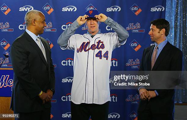 General Manager Omar Minaya watches Jason Bay and put on a New York Mets hat as Mets COO Jeff Wilpon looks on during a press conference to announce...