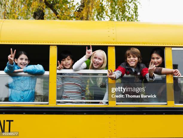 group of young students hanging out bus windows - school bus kids stock pictures, royalty-free photos & images