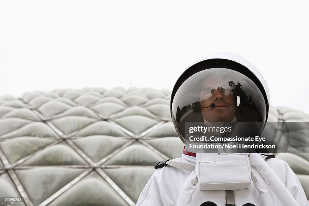 Man in space suit in front of biosphere