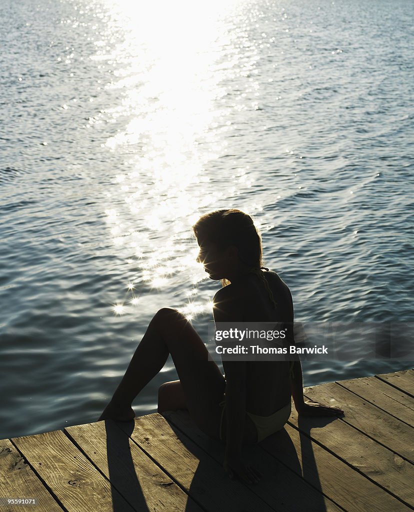 Young woman on dock with foot in water silhouette