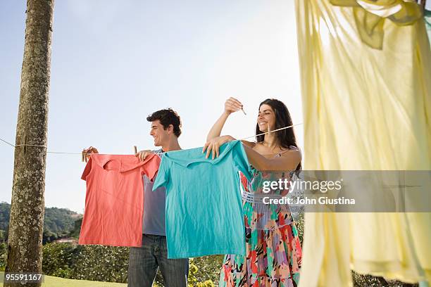 man and woman hanging up laundry to dry. - man hanging stock pictures, royalty-free photos & images