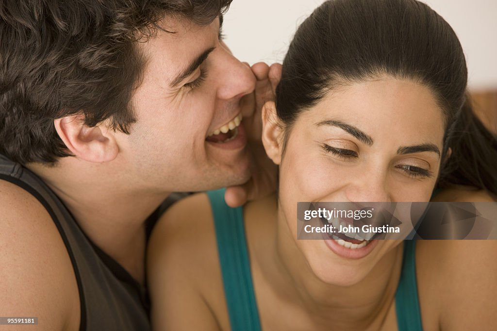 Man whispering in woman's ear.