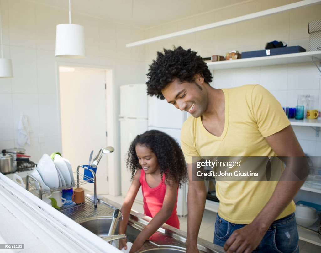 Father and daughter washing dishes.