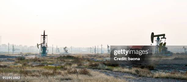 oil pumps working under the sky - oil geology stock pictures, royalty-free photos & images