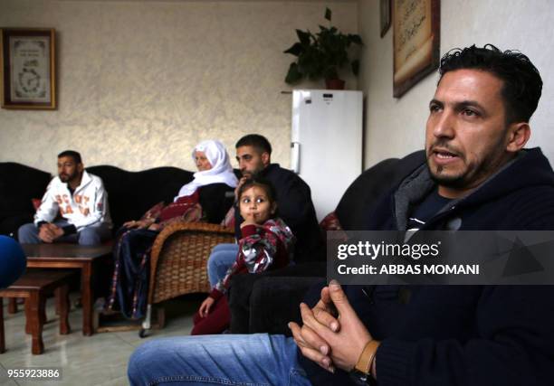 Thaer Sharkawi , 31-years-old, sits with his family members at their home in the Amari refugee camp near the West Bank city of Ramallah on May 8,...