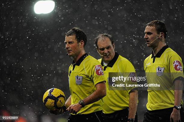 Referee Mark Clattenburg leads of his assistants in the snow during the Barclays Premier League match between Stoke City and Fulham at The Britannia...