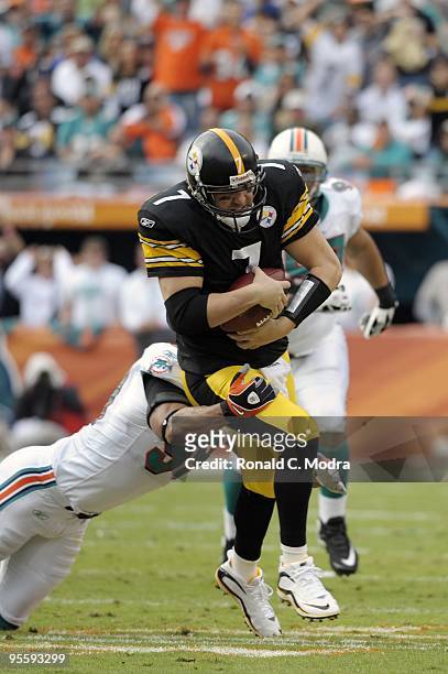 Quarterback Ben Roethlisberger of the Pittsburgh Steelers scrambles as Jason Taylor of the Miami Dolphins grabs him during a NFL game at Land Shark...