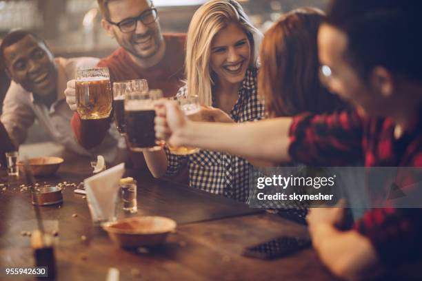 group of young joyful friends having fun while toasting with beer in a pub. - beer pub stock pictures, royalty-free photos & images