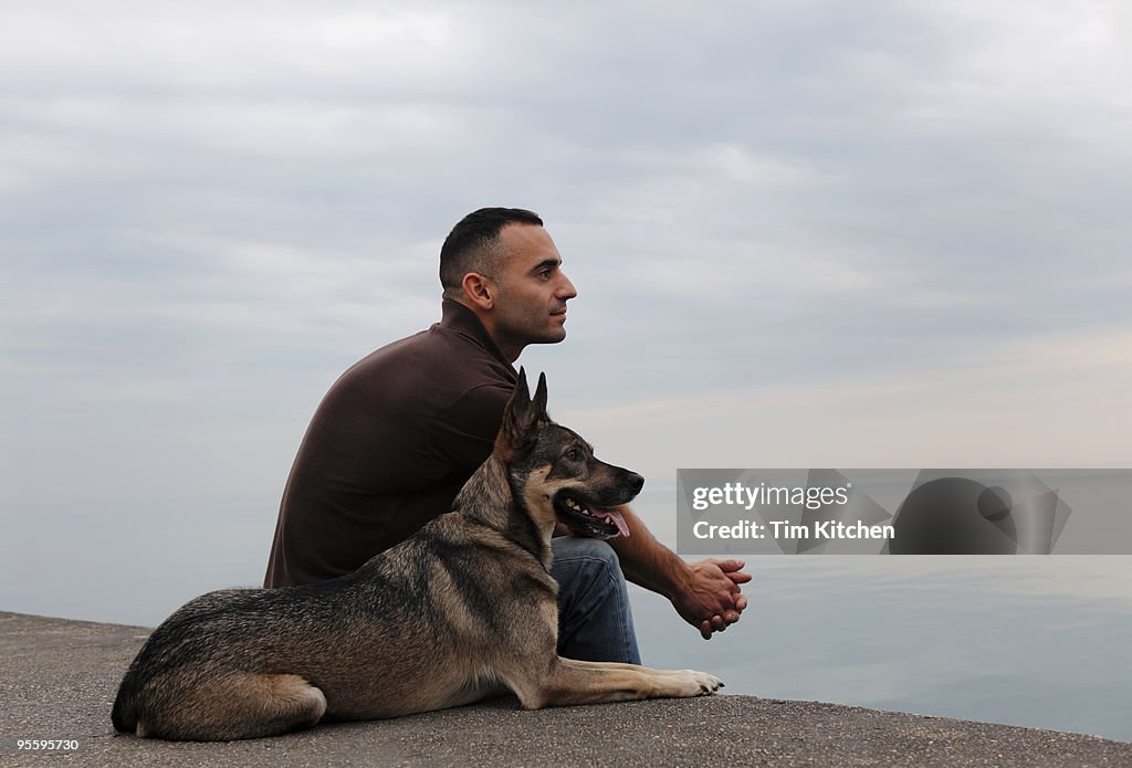 Man and dog looking over tranquil lake, profile