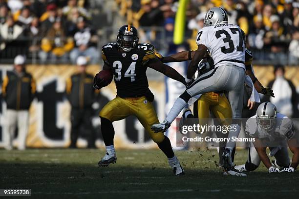 Rashard Mendenhall of the Pittsburgh Steelers carries the ball against Chris Johnson of the Oakland Raiders on December 6, 2009 at Heinz Field in...