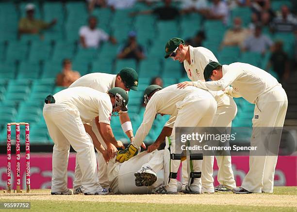 Team mates assist Nathan Hauritz of Australia after injuring his hand whilst dismissing Mohammad Yousuf of Pakistan caught and bowled during day four...