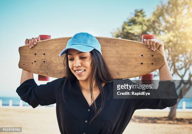 schöne junge frau mit ihrem skateboard am meer - baseballmütze stock-fotos und bilder