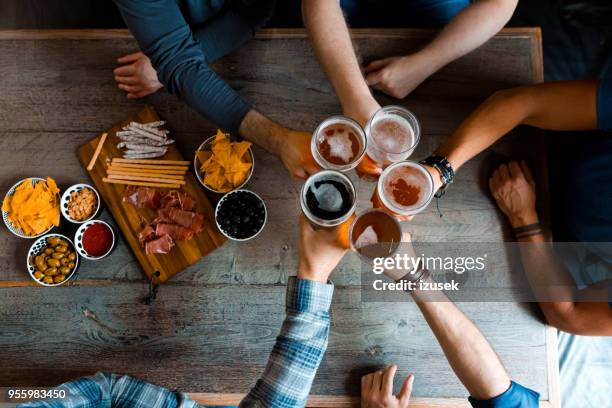 draufsicht von freunden toasten mit bier im pub über der tabelle - friends toasting above table stock-fotos und bilder