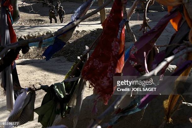 French soldiers of the 13 éme BCA pass pieces of cloth tied to a tree in memory of Afghan dead in Jalokhel in Kapisa province on January 5, 2010....