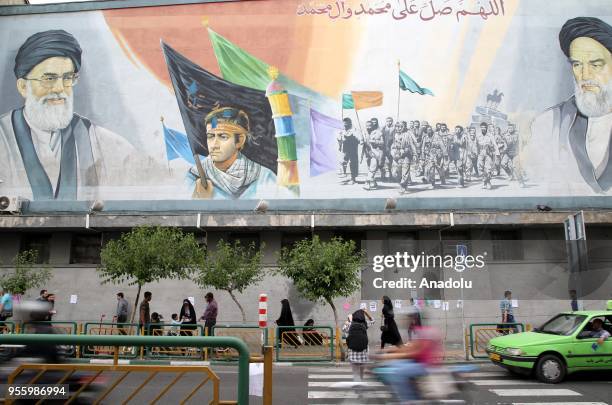 People walk past a mural painting in Tehran, Iran on May 08, 2018.