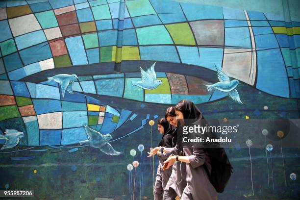 Women walk past a mural painting in Tehran, Iran on May 08, 2018.