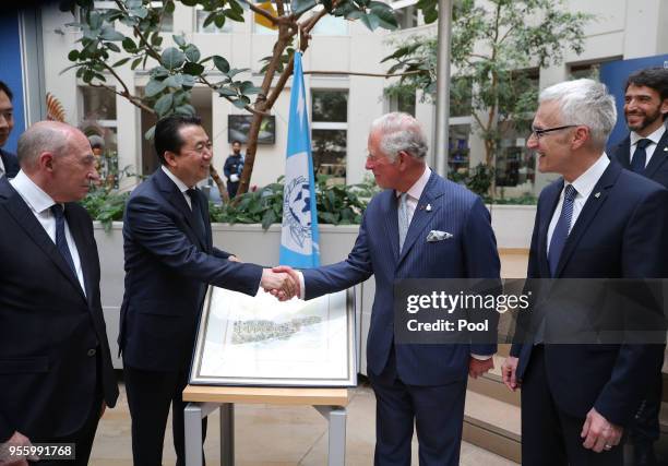Prince Charles, Prince of Wales is presented with a picture by the President of Interpol Meng Hongwei during Prince Charles's tour of Interpol on May...