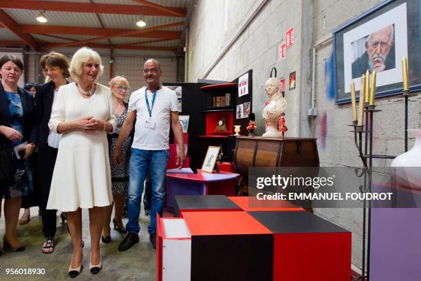 Britain's Camilla , Duchess of Cornwall, looks at a picture of Catholic priest Abbe Pierre as she visits a second-hand shop of the Emmaus solidarity...