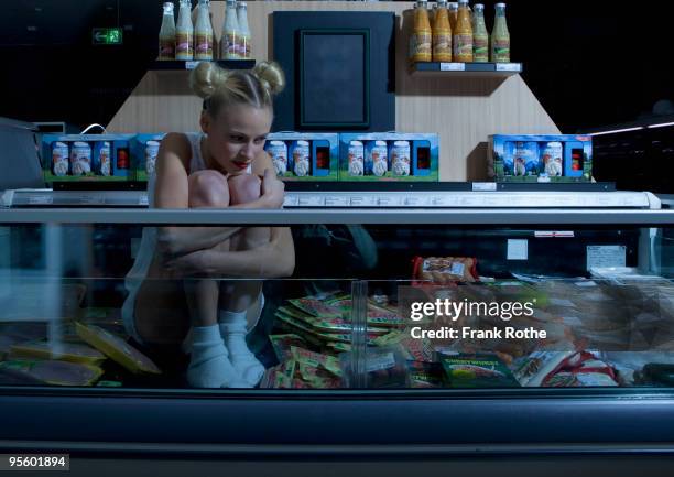 young woman looking cold in freezer - supermarket refrigeration stock-fotos und bilder