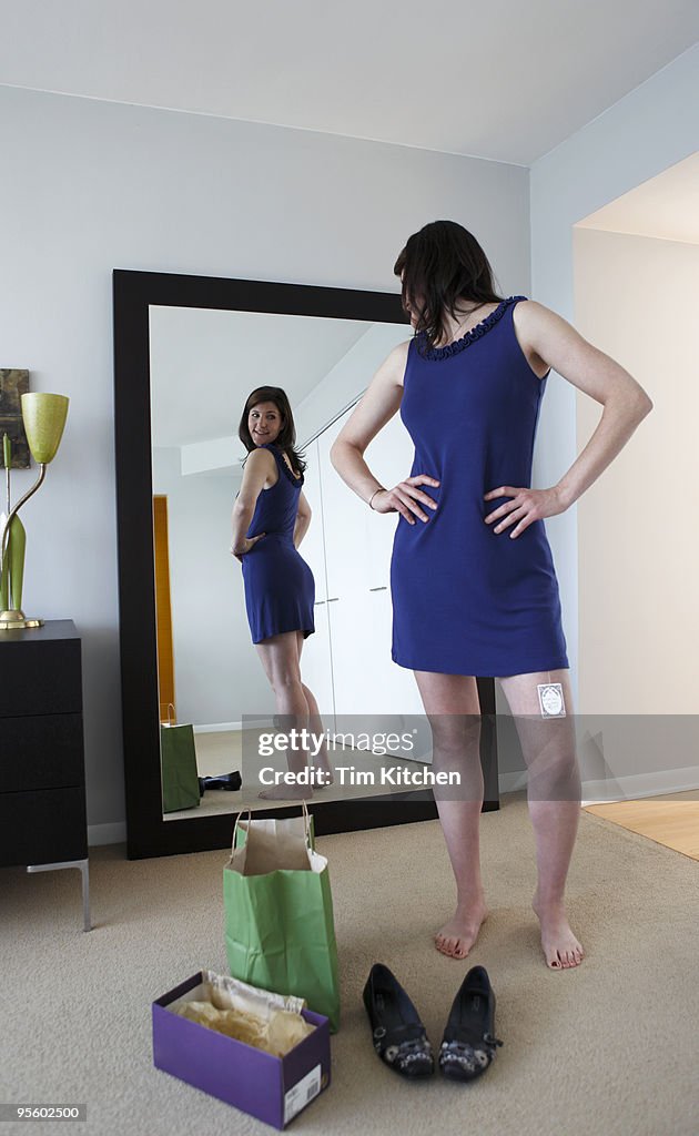 Woman wearing new dress, looking in mirror