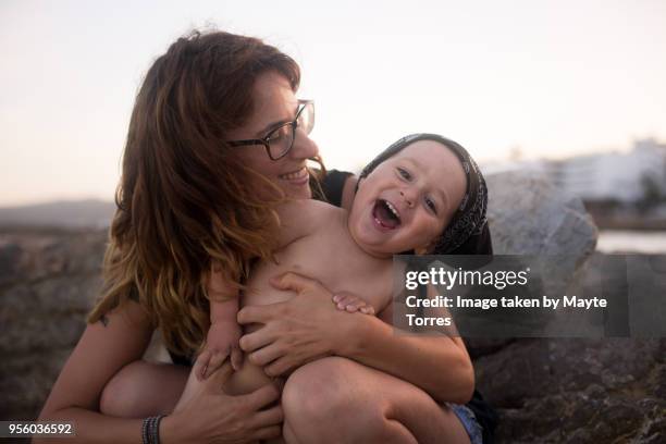 mum tickling baby boy at the beach - baby suncream stock pictures, royalty-free photos & images