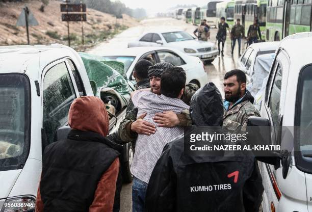 Syrians evacuated from rebel-held areas from Syria's central Homs province in a convoy of buses greet loved ones as they arrive at Abu al-Zandin...