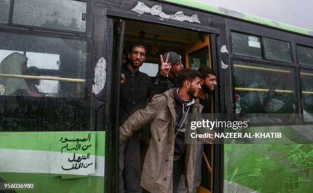 Syrians evacuated from rebel-held areas from Syria's central Homs province in a convoy of buses flashes the victory gesture as he arrives at Abu...