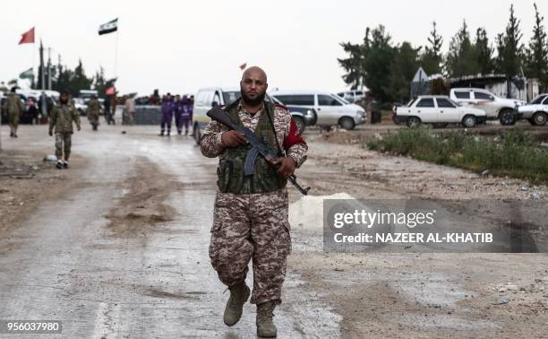 Turkey-backed Syrian fighter walks in Abu al-Zandin checkpoint near al-Bab in northern Syria on May 8 as a convoy of buses carrying people evacuated...