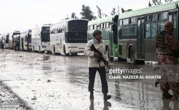 Turkey-backed Syrian fighter walks in Abu al-Zandin checkpoint near al-Bab in northern Syria on May 8 as a convoy of buses carrying people evacuated...