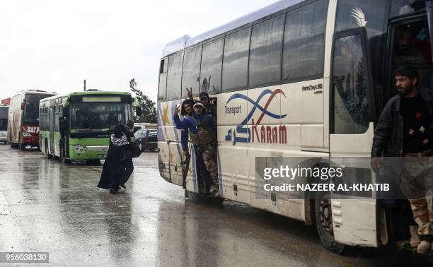 Syrians evacuated from rebel-held areas from Syria's central Homs province flash the victory gesture as their convoy of buses arrives at Abu...