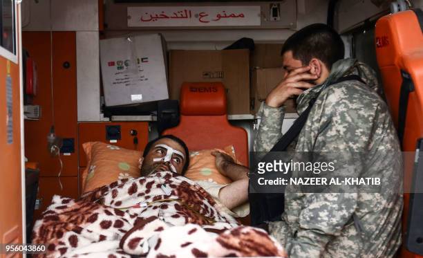 Syrian Turkey-backed fighter sits next to an injured man in an ambulance after the latter arrived at Abu al-Zandin checkpoint near al-Bab in northern...
