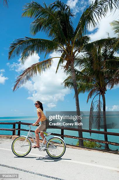 a woman rides a bicycle in florida. - florida keys stock pictures, royalty-free photos & images
