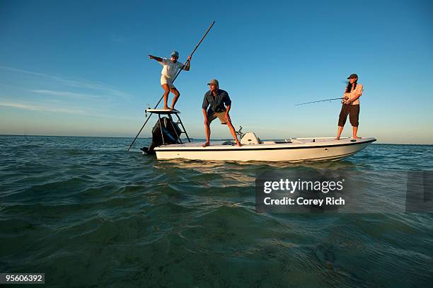 a woman fishes while one man watches and one man pilots the boat in florida. - florida angeln stock-fotos und bilder